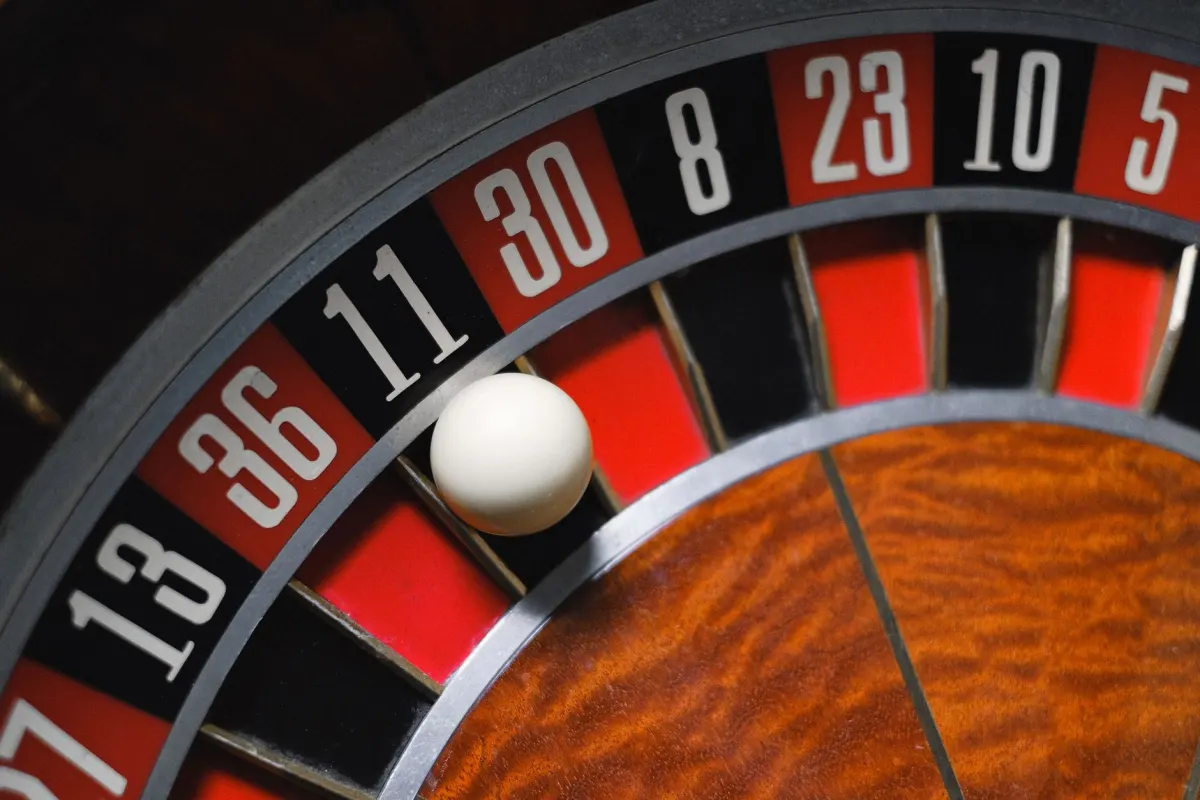 Close-up of a single-zero roulette wheel with the ball resting in the pocket below 11, showing the pocket sequence 27, 13, 36, 11, 30, 8, 23, 10, 5 in alternating red and black